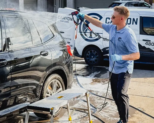 Canyon Car Care detailer pressure washing an SUV next to the Canyon Car Care van